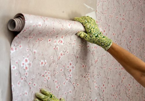 In,Female,Hands,,A,Roll,Of,Wallpaper,On,The,Wall